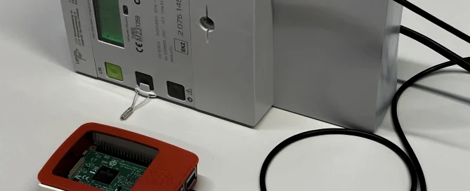 A Raspberry Pi is connected to an industrial electricity meter via a black USB cable.