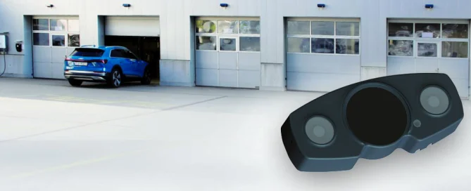A blue car exits a garage; a black sensor device for industrial automation is visible in the foreground.