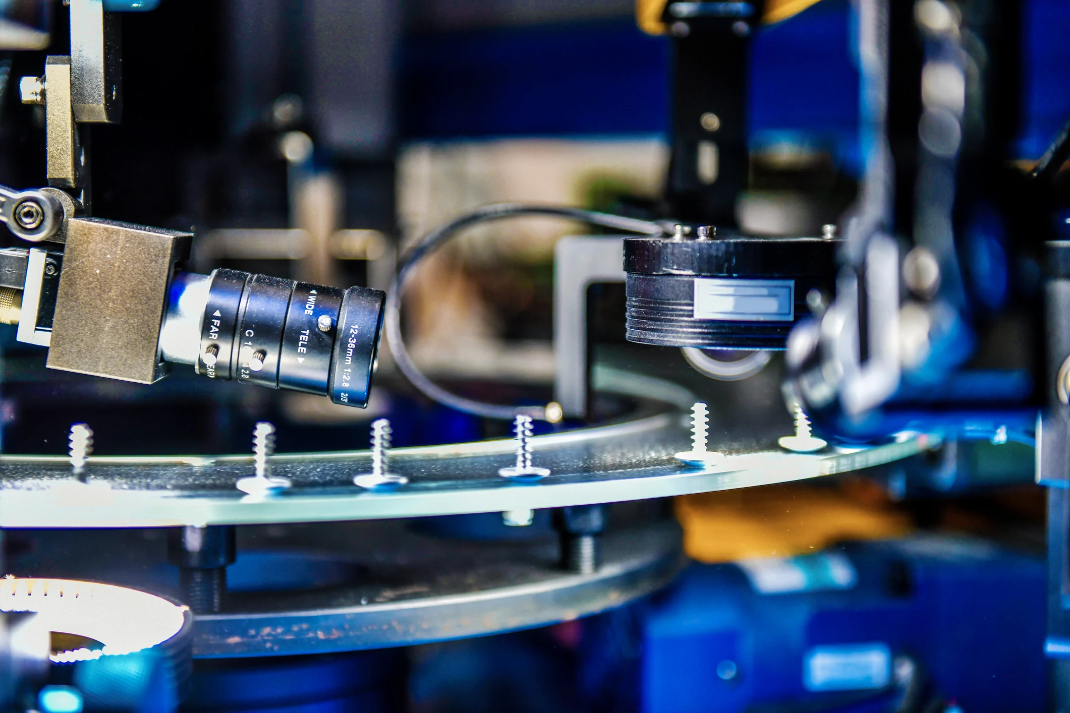 Close-up of machines using machine vision to inspect screws on a glass plate. Close-up of machines using machine vision to inspect screws on a glass plate.