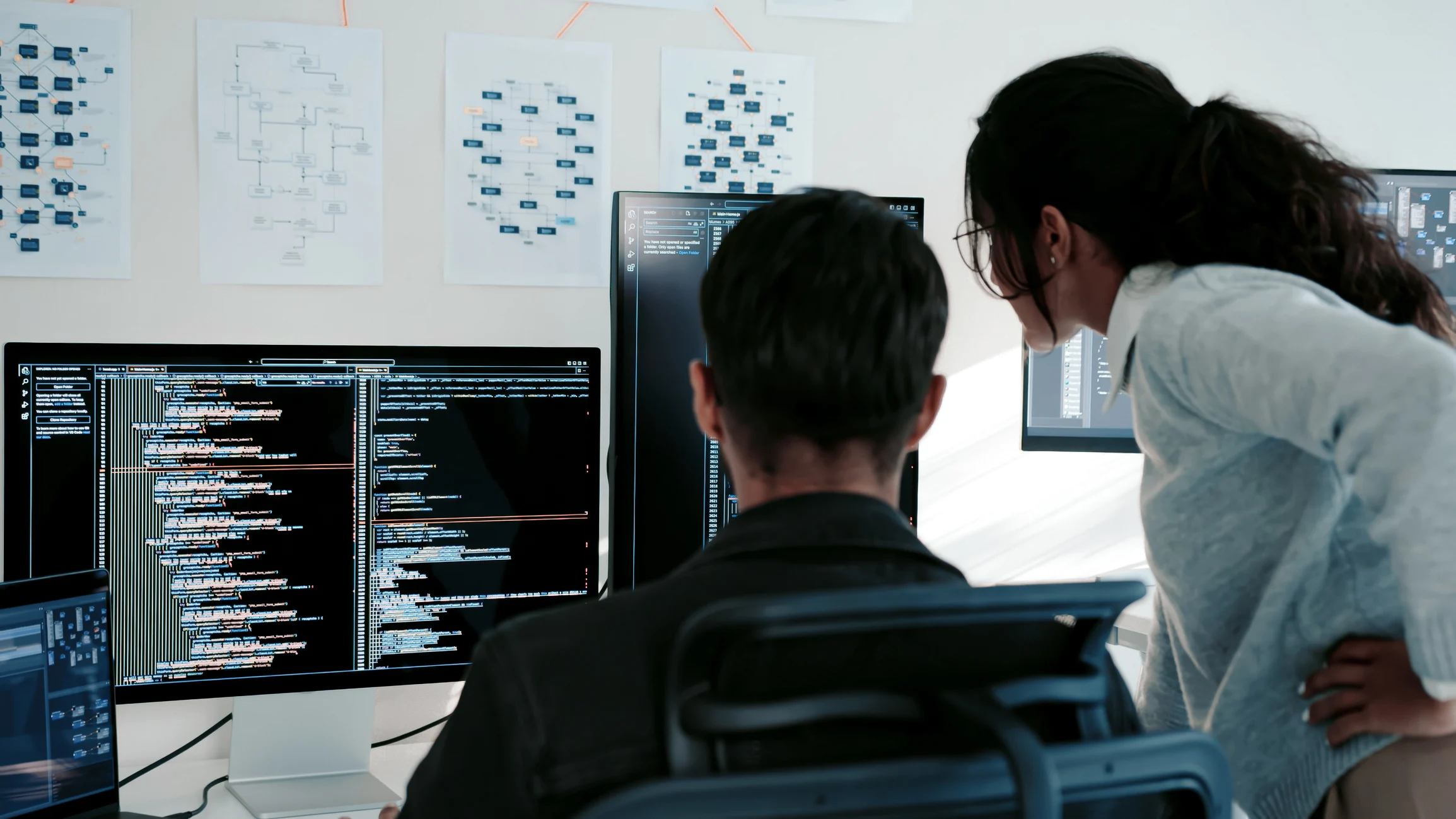 Zwei Personen überprüfen DevOps-Code auf ihren Bildschirmen; hinter ihnen sind Diagramme an der Wand zu sehen. Zwei Personen überprüfen DevOps-Code auf ihren Bildschirmen; hinter ihnen sind Diagramme an der Wand zu sehen.